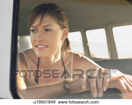 Stock Photo - Woman in sitting in front seat of van, head and shoulders, view through window. Fotosearch