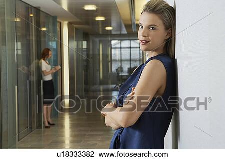 Woman leaning against wall in office corridor, portrait View Large Photo Image Stock Image - Woman leaning against wall in office corridor, portrait. Fotosearch