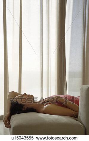 Woman lying back on sofa in living room View Large Photo Image Stock Photography - Woman lying back on sofa in living room. Fotosearch
