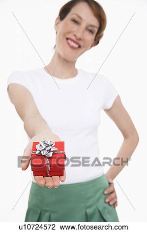 Stock Image - Woman offering small gift wrapped present. Fotosearch