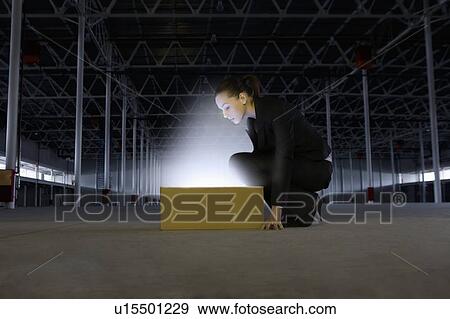 Woman peers into yellow box shining bright light View Large Photo Image Stock Photo - Woman peers into yellow box shining bright light. Fotosearch