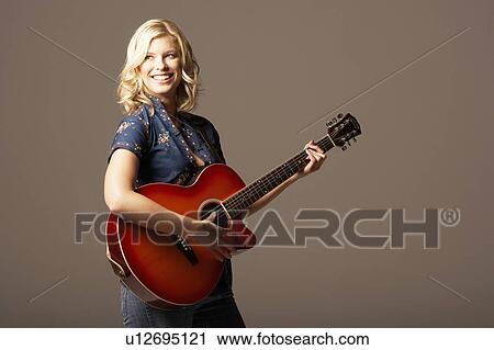 Stock Image - Woman Playing Guitar, smiling, looking away. Fotosearch