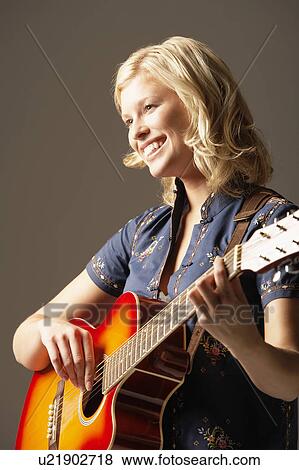 Stock Photo - Woman Playing Guitar, smiling, low angle view. Fotosearch