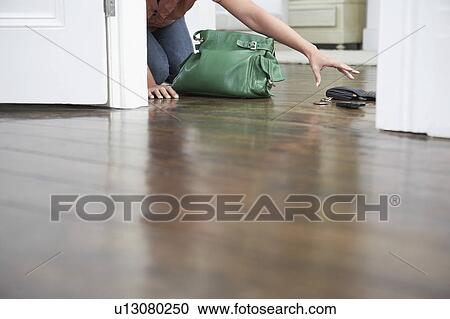 Stock Image - Woman reaching for spilled purse on floor. Fotosearch