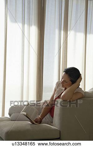 Woman reading book, reclining on sofa View Large Photo Image Stock Photography - Woman reading book, reclining on sofa. Fotosearch