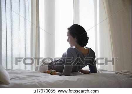 Woman reclining on bed in bedroom View Large Photo Image Stock Photography - Woman reclining on bed in bedroom. Fotosearch