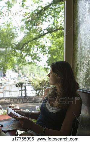 Stock Photograph - Woman sits at window of Amsterdam cafe looking at view. Fotosearch