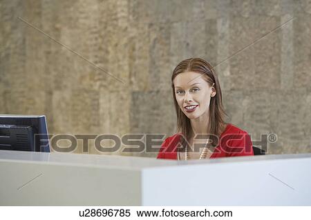 Stock Photography - Woman sitting at desk, portrait. Fotosearch