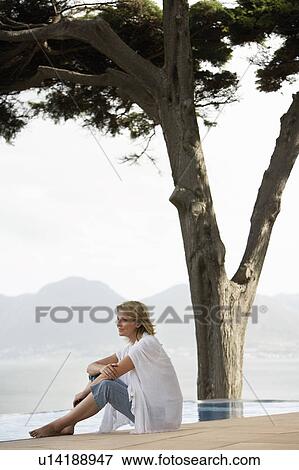 Woman sitting by infinity pool, side view View Large Photo Image Stock Photo - Woman sitting by infinity pool, side view. Fotosearch