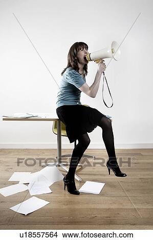 Woman sitting on desk, shouting through megaphone View Large Photo Image Picture - Woman sitting on desk, shouting through megaphone. Fotosearch