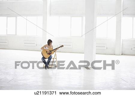 Woman sitting with accoustic guitar in empty warehouse View Large Photo Image Stock Image - Woman sitting with accoustic guitar in empty warehouse. Fotosearch