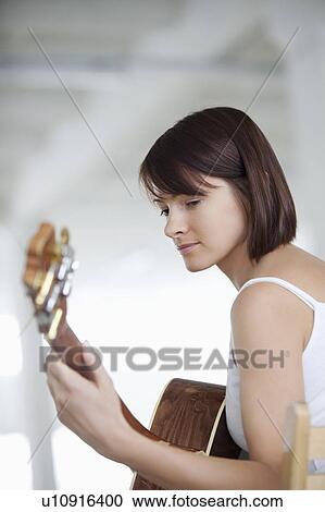 Stock Image - Woman sitting with accoustic guitar. Fotosearch