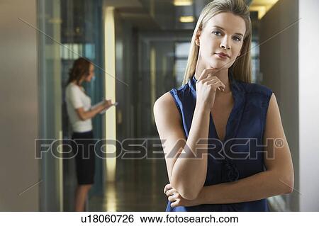 Stock Photograph - Woman standing in office corridor, portrait. Fotosearch