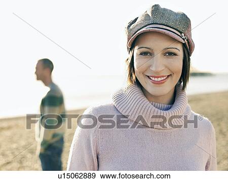 Woman standing on beach, head and shoulders, man behind View Large Photo Image Stock Photo - Woman standing on beach, head and shoulders, man behind. Fotosearch