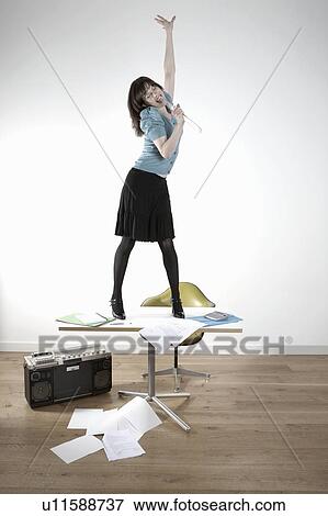 Woman standing on desk and singing View Large Photo Image Stock Photo - Woman standing on desk and singing. Fotosearch