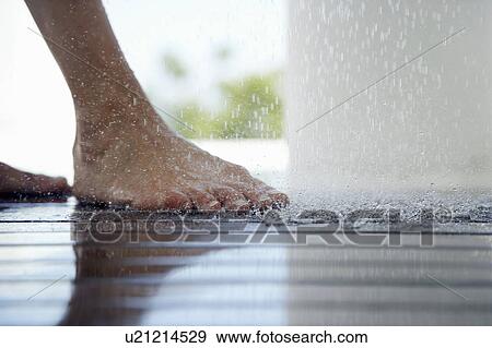 Stock Photo - Woman standing under outdoor shower, close up of feet, low section, . Fotosearch