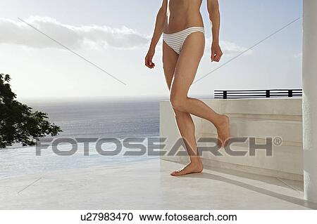 Stock Image - Woman walking down steps on outdoor terrace, low section. Fotosearch