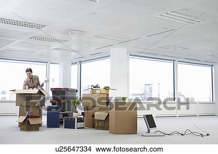 Picture - Woman with Cardboard Boxes in Empty Office Space. Fotosearch