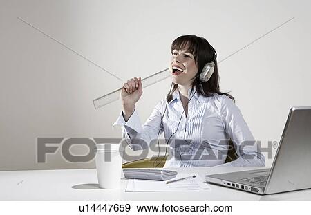 Woman with earphones fooling around at desk View Large Photo Image Stock Photo - Woman with earphones fooling around at desk. Fotosearch