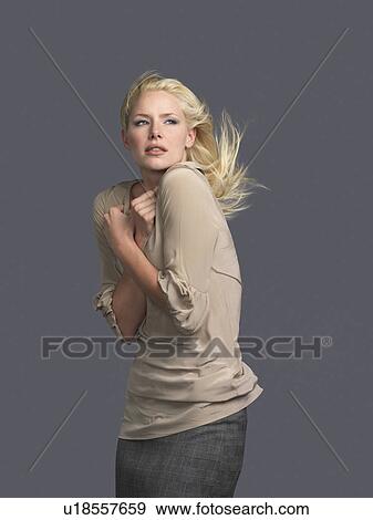Stock Photo - Woman with hair blowing, arms crossed, side view. Fotosearch