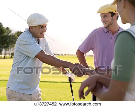 Yong golfers shaking hands on course View Large Photo Image Stock Image - Yong golfers shaking hands on course. Fotosearch