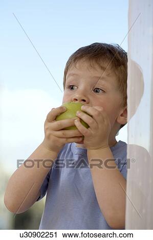 Stock Image - Young boy biting into an apple. Fotosearch