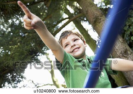 Young Boy sitting on monkey bars pointing, close up View Large Photo Image Stock Image - Young Boy sitting on monkey bars pointing, close up. Fotosearch