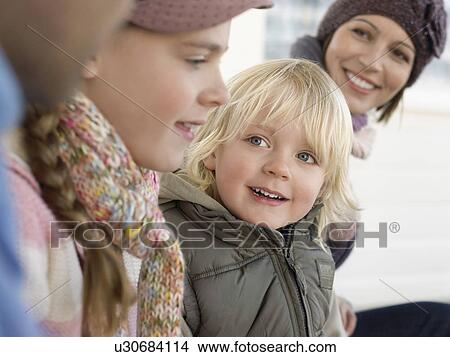 Picture - Young boy sitting with family, outdoors, close up. Fotosearch