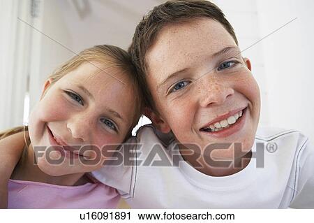 Stock Image - Young boy with arm around young girl, portrait, close-up. Fotosearch