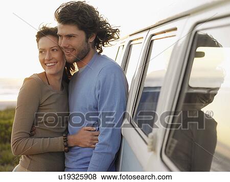 Young couple embracing by van parked by ocean, half length View Large Photo Image Stock Photo - Young couple embracing by van parked by ocean, half length. Fotosearch