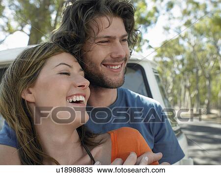 Young couple embracing, leaning against front of van parked by road, head and shoulders View Large Photo Image Stock Photography - Young couple embracing, leaning against front of van parked by road, head and shoulders. Fotosearch