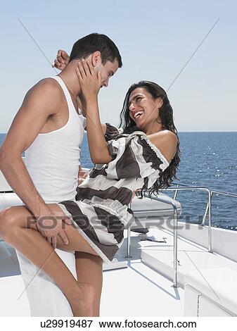 Stock Photo - Young couple embracing on yacht, side view. Fotosearch
