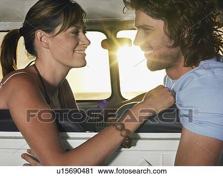 Stock Image - Young couple face to face in front seat of van. Fotosearch