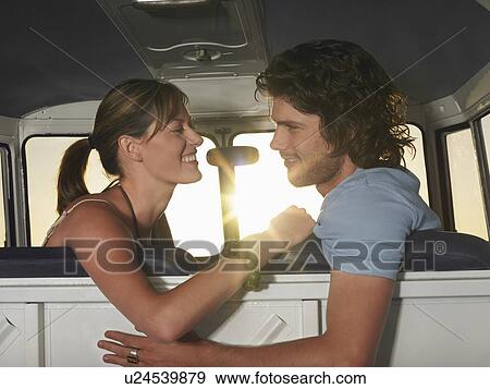 Stock Photo - Young couple face to face in front seat of van. Fotosearch