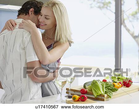 Young couple hugging in kitchen near countertop with fresh produce and wineglasses View Large Photo Image Stock Photo - Young couple hugging in kitchen near countertop with fresh produce and wineglasses. Fotosearch