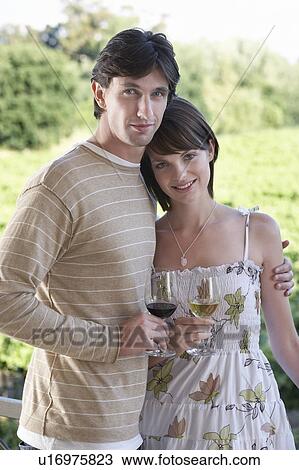 Stock Image - Young couple on terrace holding wine glasses. Fotosearch