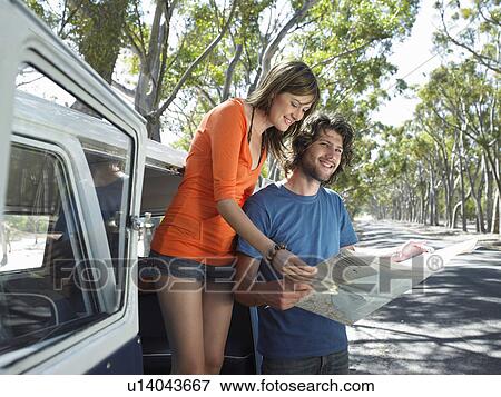 Stock Photo - Young Couple Reading Map on Road Trip. Fotosearch