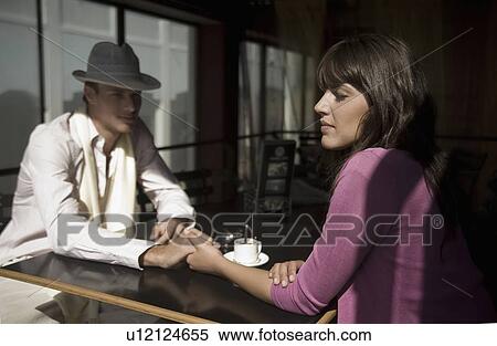 Stock Photography - Young couple sit holding hands in cafe. Fotosearch