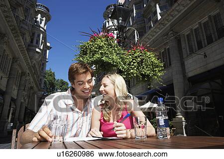Young couple sitting at outdoor cafe writing postcard View Large Photo Image Stock Photograph - Young couple sitting at outdoor cafe writing postcard. Fotosearch