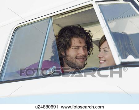Stock Image - Young couple smiling at each other in van, head and shoulders. Fotosearch