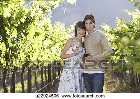 Young couple with wine glasses in vineyard View Large Photo Image Stock Photograph - Young couple with wine glasses in vineyard. Fotosearch