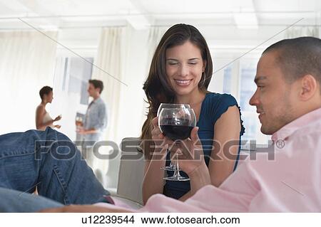 Young couples drinking wine in living room View Large Photo Image Picture - Young couples drinking wine in living room. Fotosearch