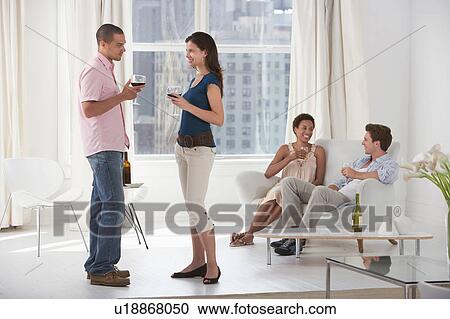 Young couples drinking wine in living room View Large Photo Image Stock Image - Young couples drinking wine in living room. Fotosearch