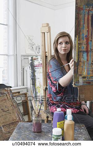 Young female art student painting at easel in art studio View Large Photo Image Picture - Young female art student painting at easel in art studio. Fotosearch