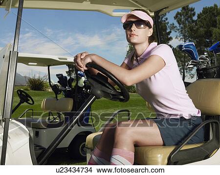 Picture - Young female golfer in sitting in cart. Fotosearch