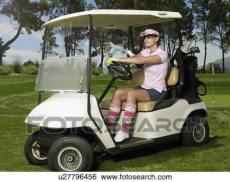Stock Photograph - Young female golfer in sitting in cart. Fotosearch