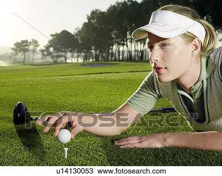 Young female golfer lying on court, placing ball on tee View Large Photo Image Stock Image - Young female golfer lying on court, placing ball on tee. Fotosearch