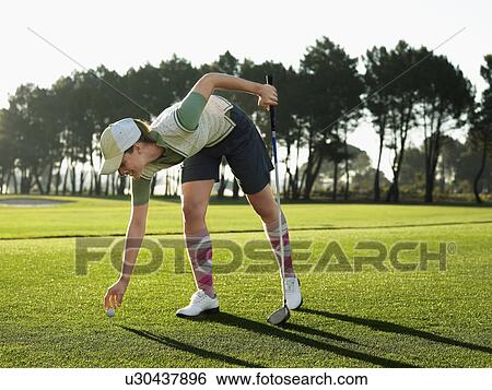 Young female golfer placing ball on tee View Large Photo Image Stock Photograph - Young female golfer placing ball on tee. Fotosearch