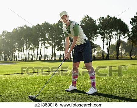 Stock Photograph - Young female golfer teeing off. Fotosearch