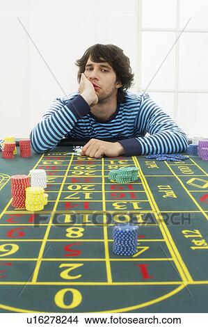 Picture - Young frustrated man at roulette table. Fotosearch
